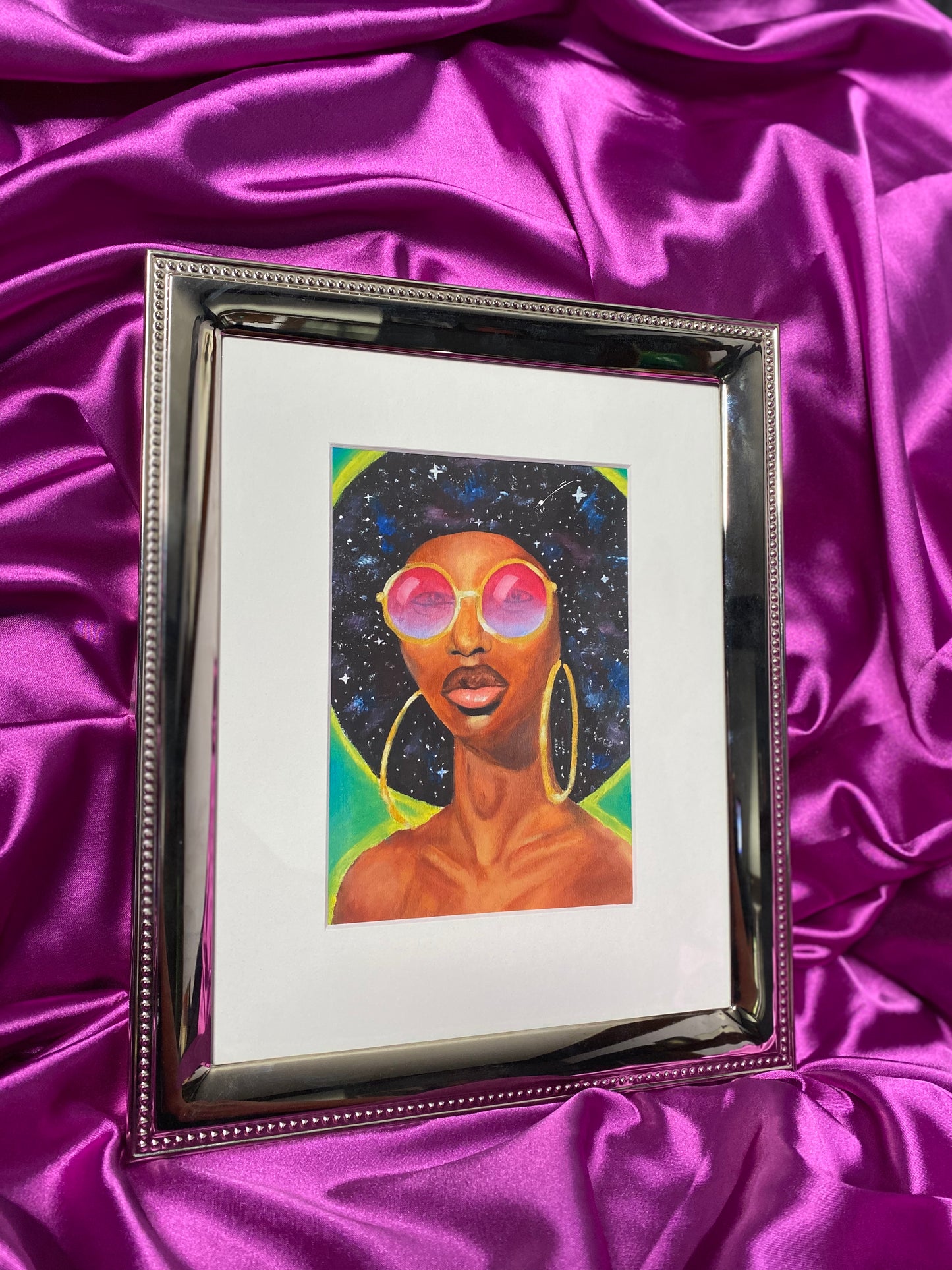 Framed artwork of a person with sunglasses on a purple satin background